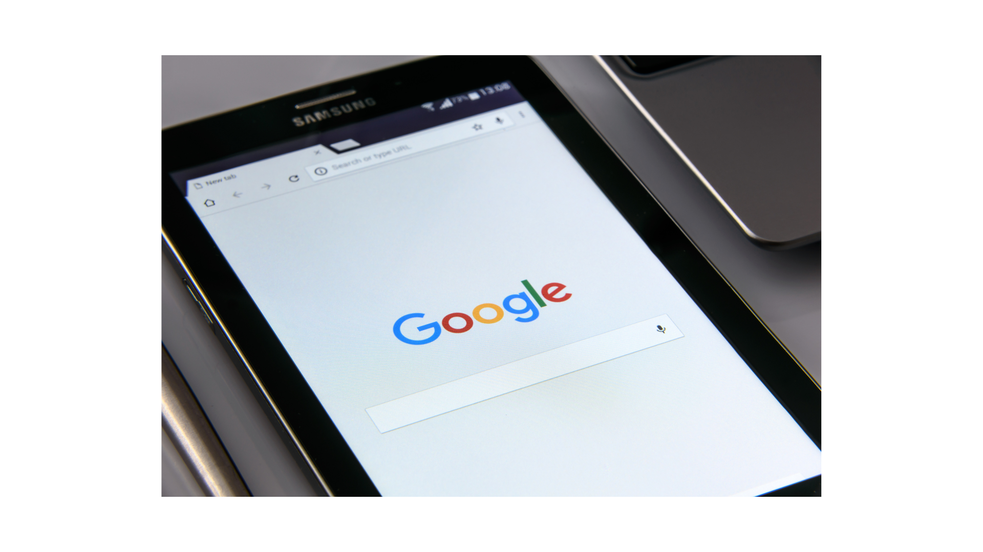 Samsung tablet screen displaying the Google search homepage on a table.